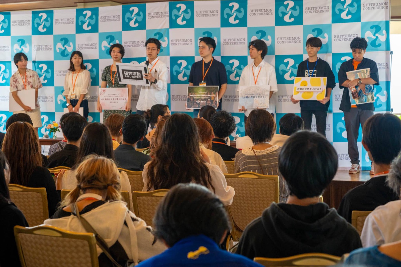 前回招待した学生たちがステージで話す様子